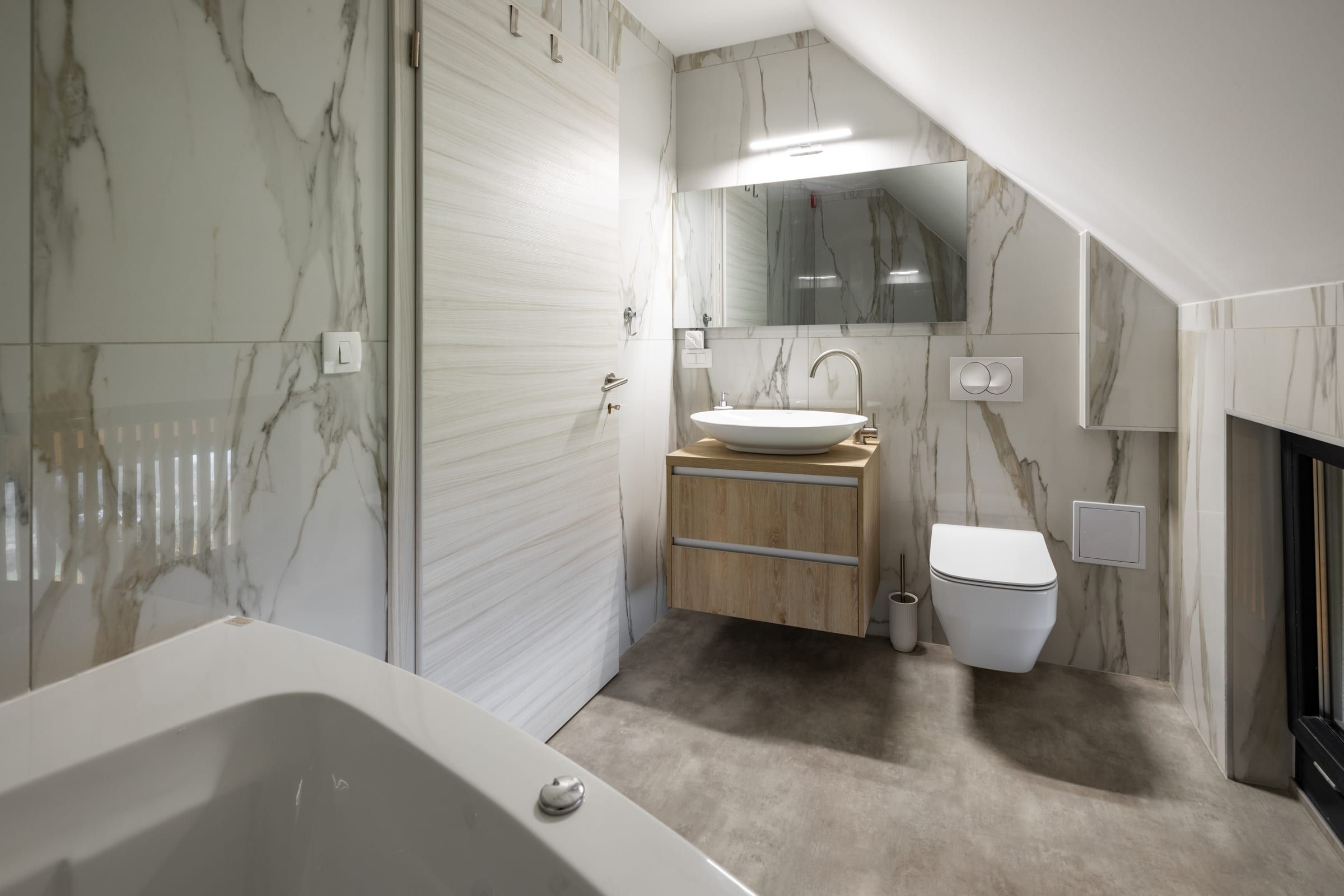 The bathroom vanity with a countertop basin and oak cabinet, beside the bathtub.
