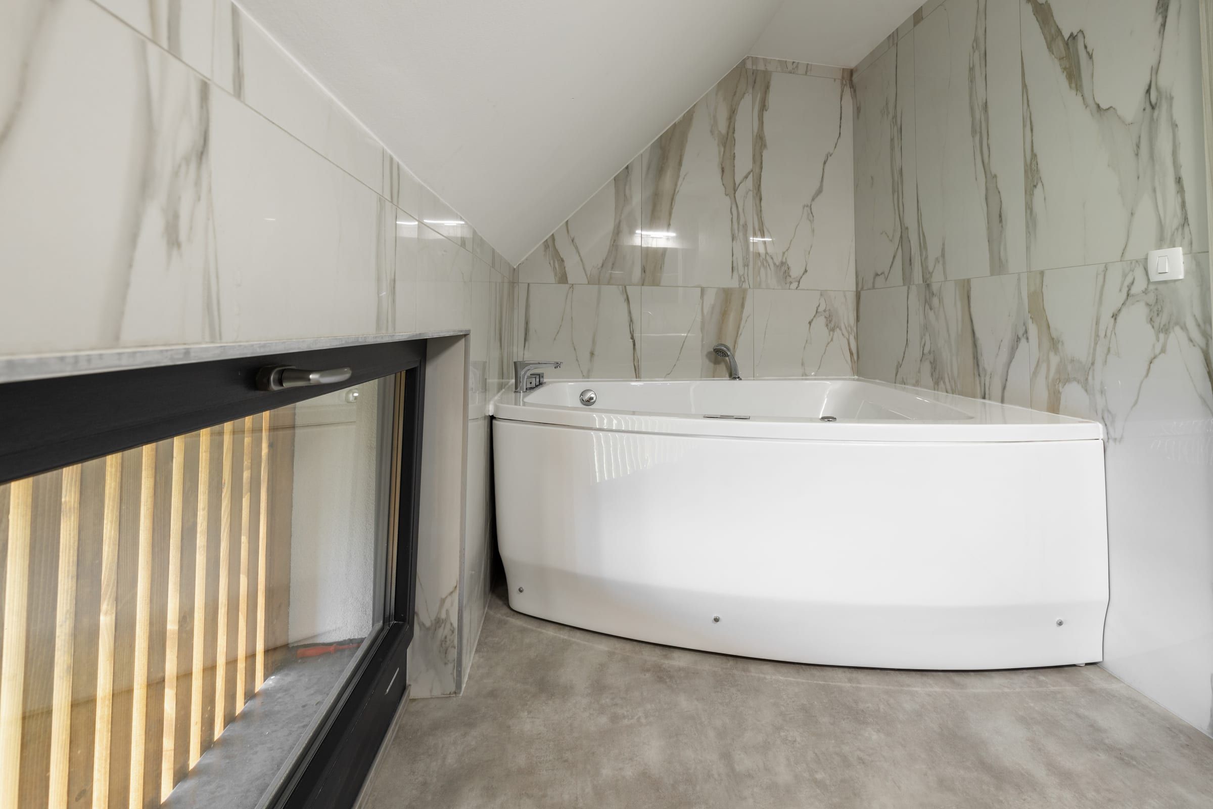 The full bathroom's corner bathtub, finished in marble-look tile.