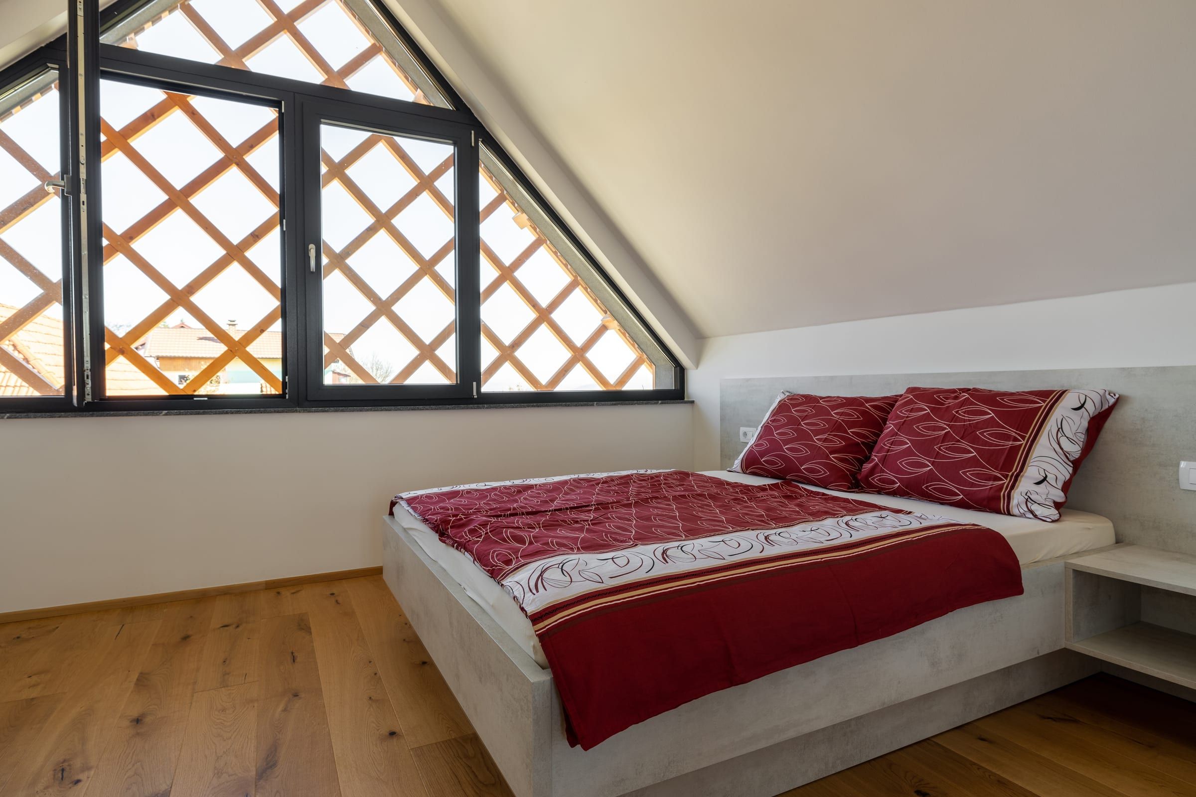 A double bedroom under the villa's diamond-latticed gable window.