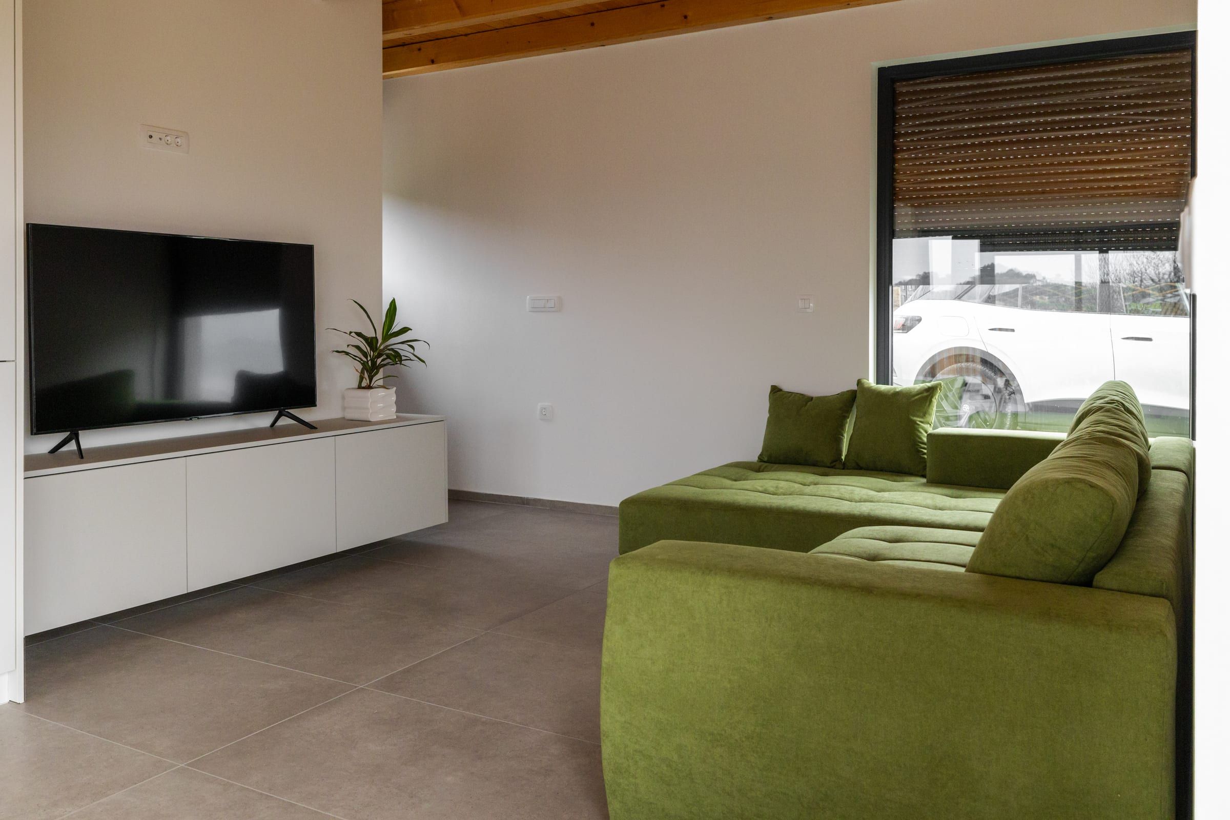 The green corner sofa in the living room beside a large picture window.