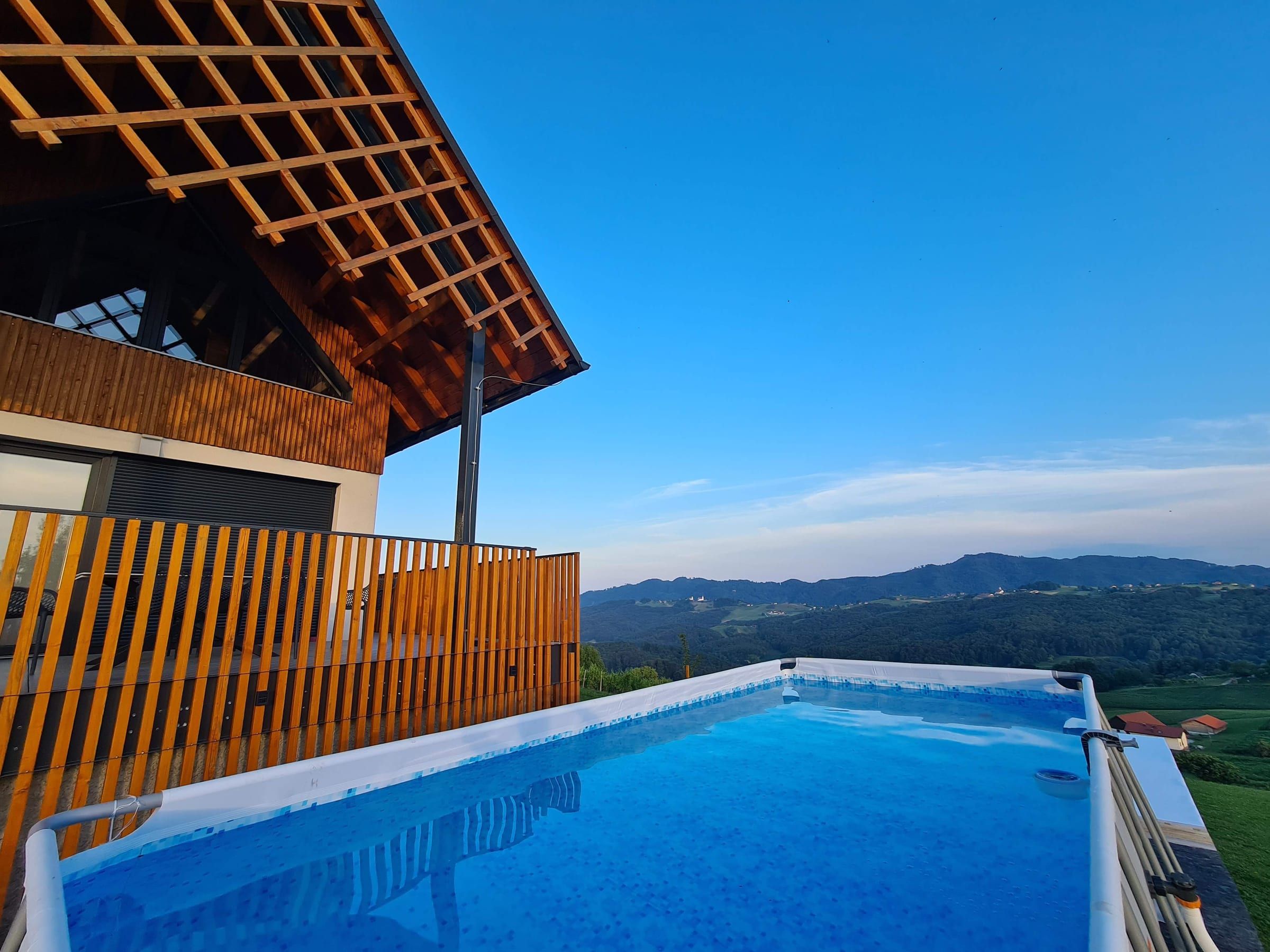 The pool at dusk with the wooded hills beyond in soft evening light.