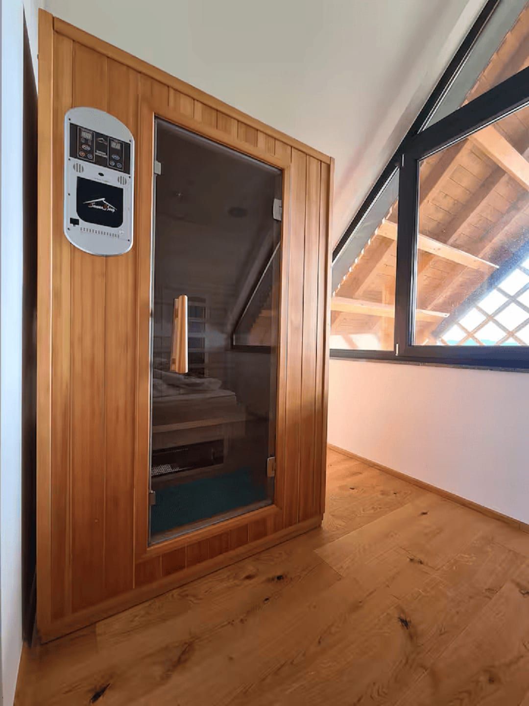 The timber infrared sauna cabin set beneath the sloped ceiling and window.
