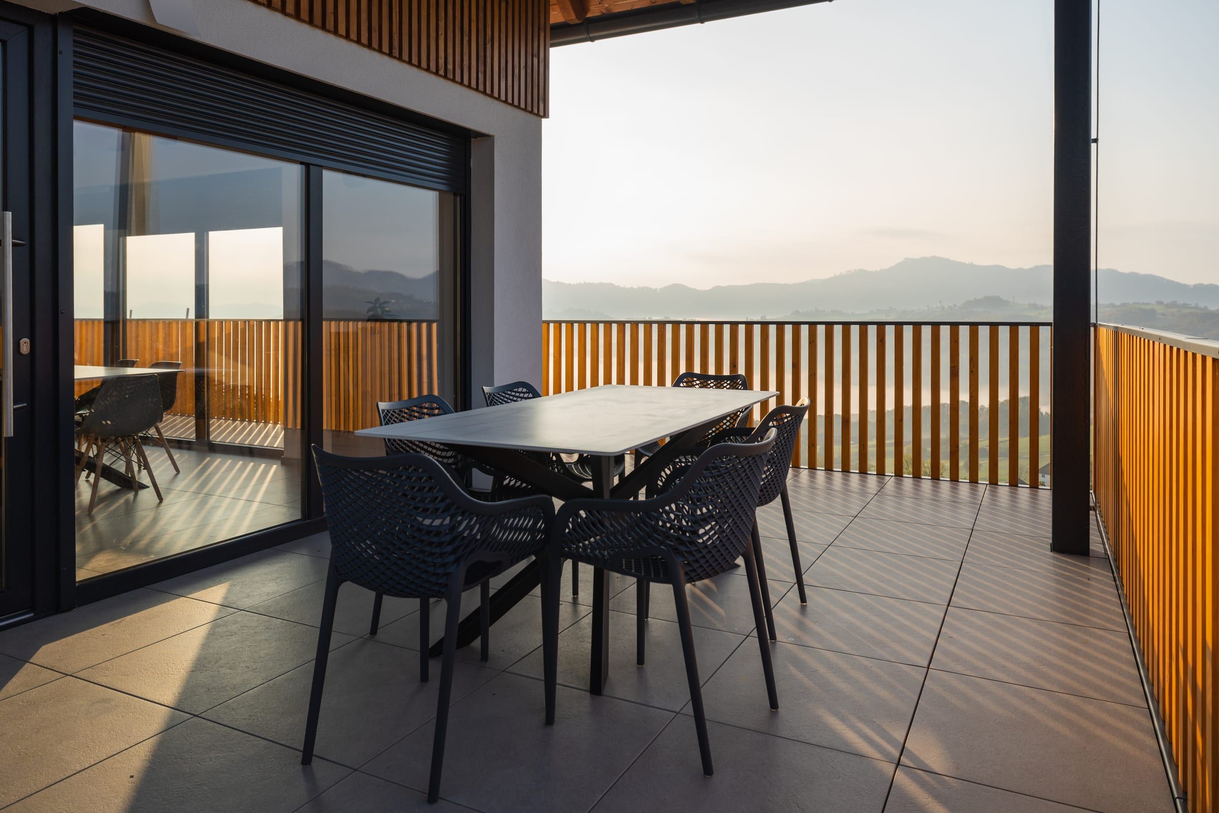 The terrace table and chairs under the timber canopy at golden hour.