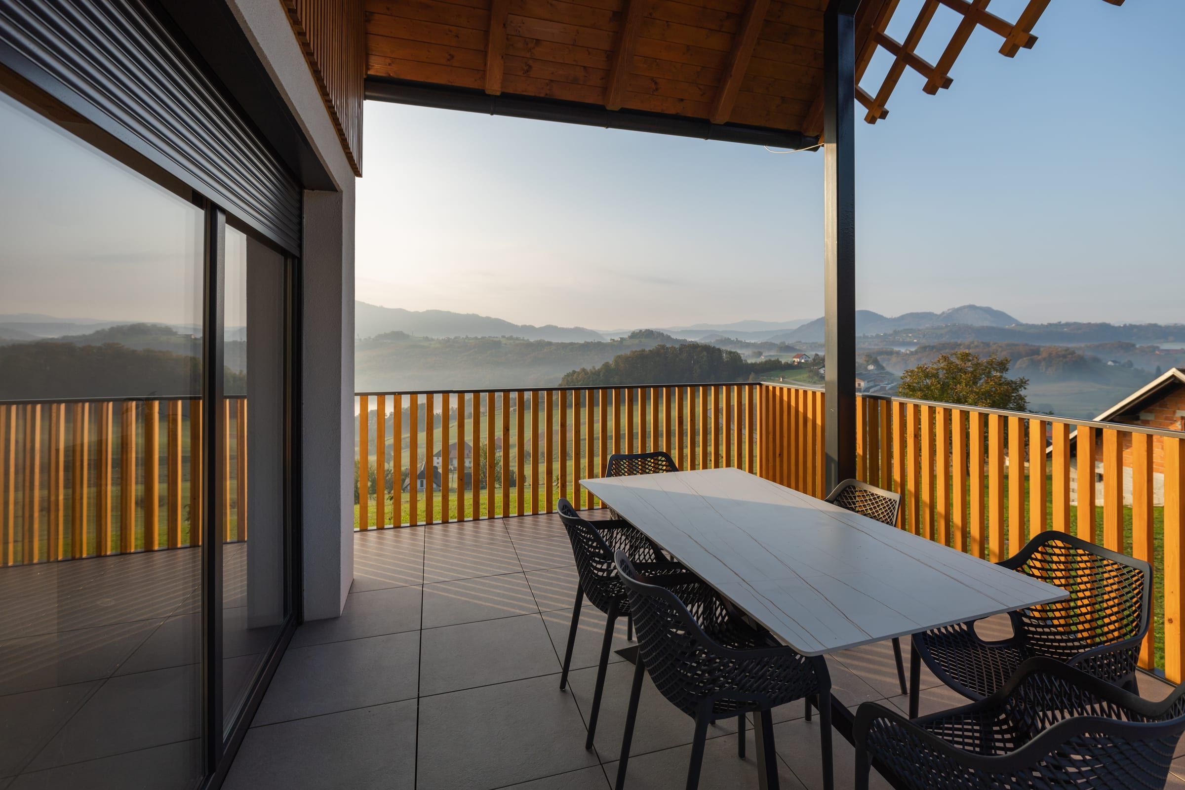 The covered terrace dining table at sunrise, with views over the hills.