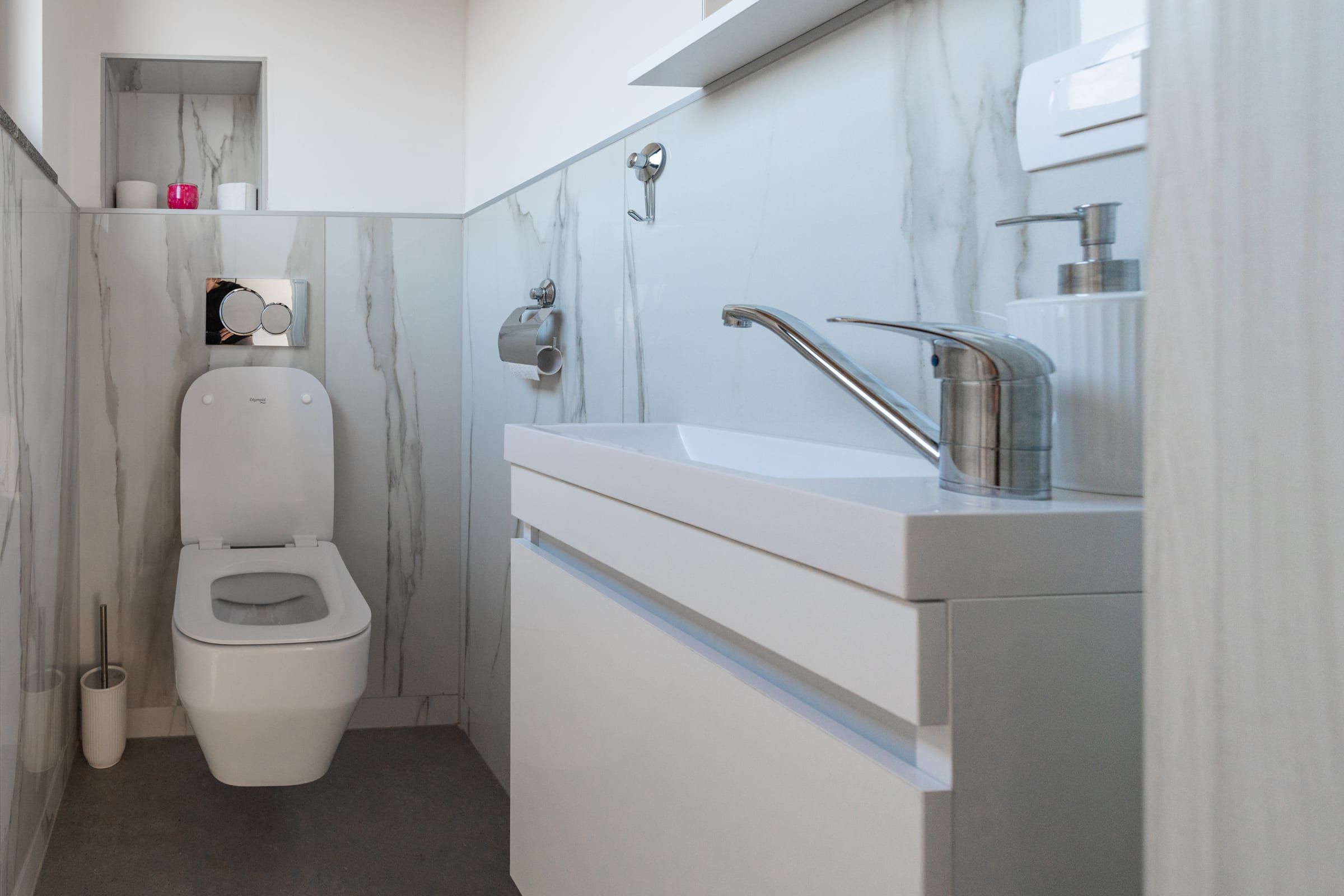 The separate WC with basin, finished in marble-look tile.